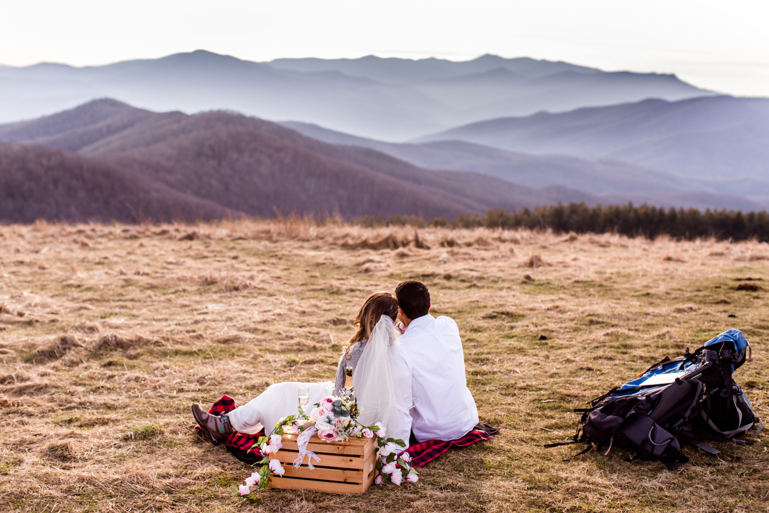 bride and groom on top of a mountain looking at a beautiful sunset